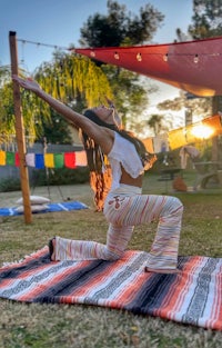 a woman doing yoga on a blanket in a backyard