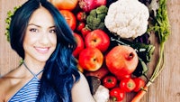 a woman posing in front of a bunch of vegetables